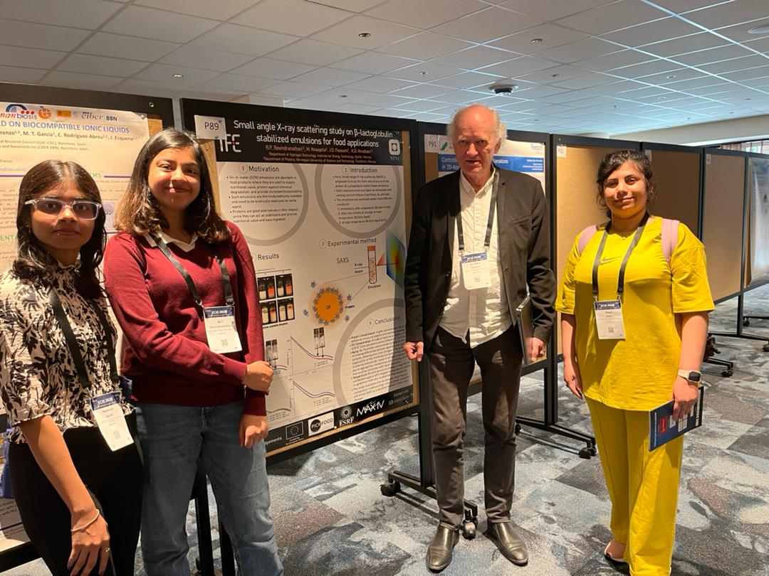 Three women and one man in front of a poster